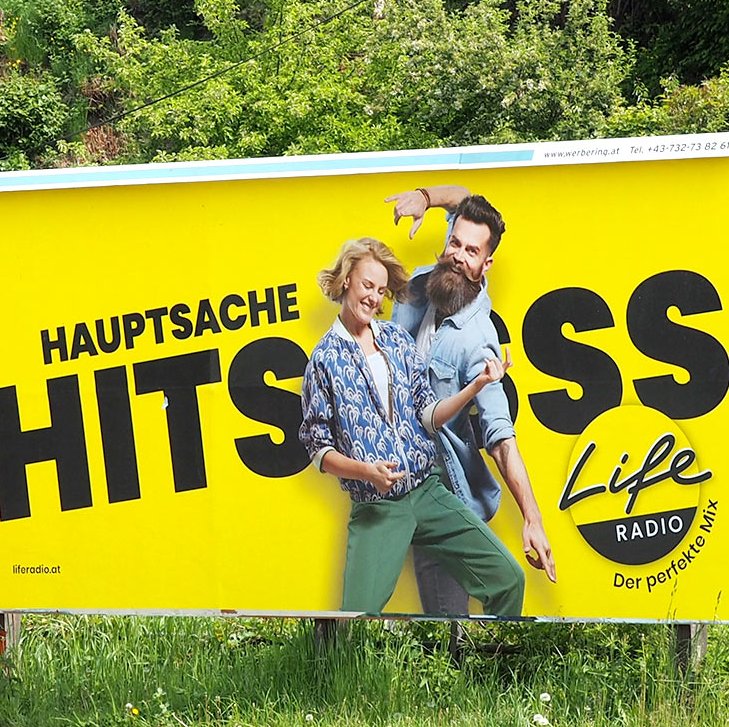 24-Bogen-Plakat, Life Radio, Frau und Mann tanzen im Vordergrund, gelber Hintergrund und schwarzer Text