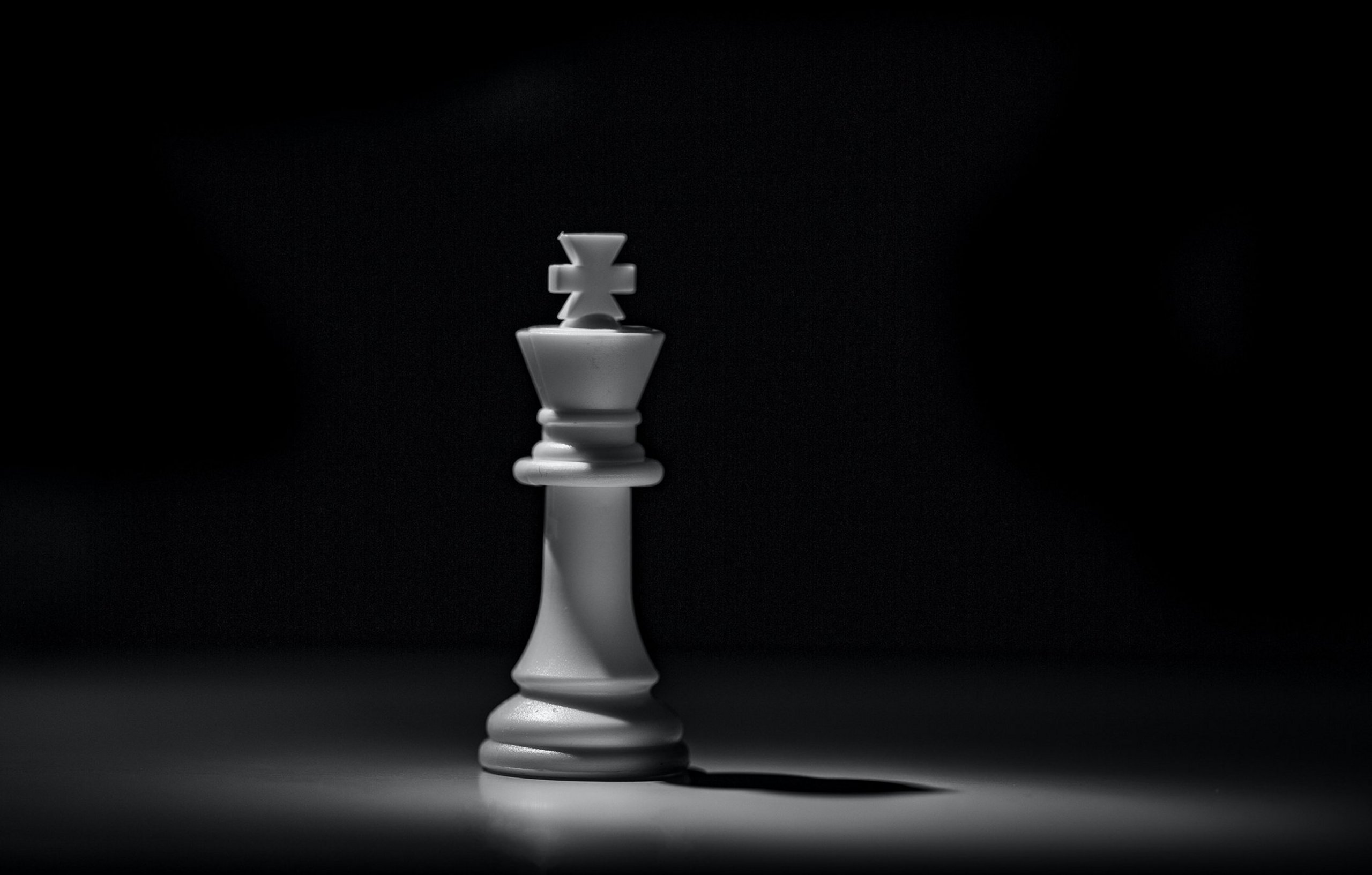 König Schachfigur in Weiß vor schwarzem Hintergrund