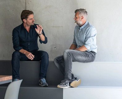 Zwei Männer sitzen und besprechen