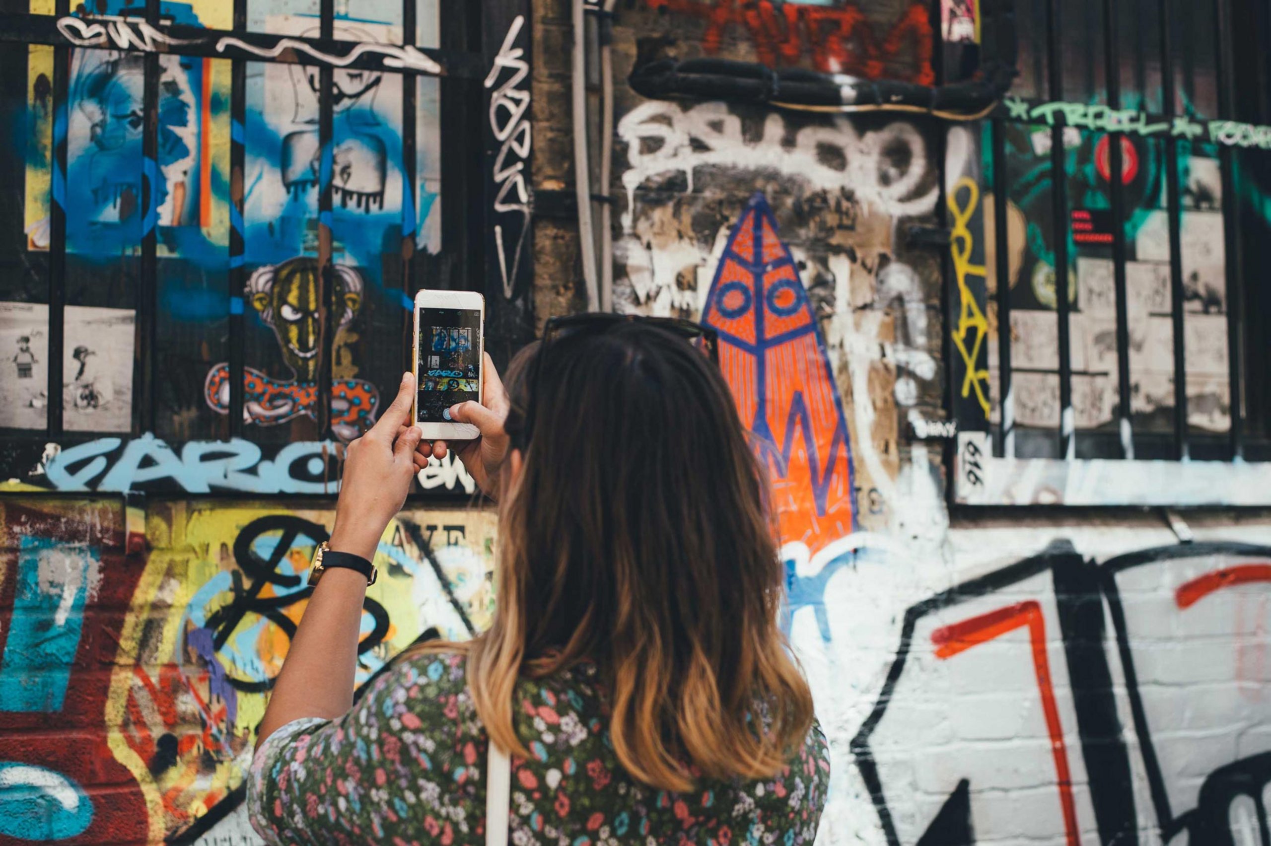 Frau steht vor Graffiti mit Handy