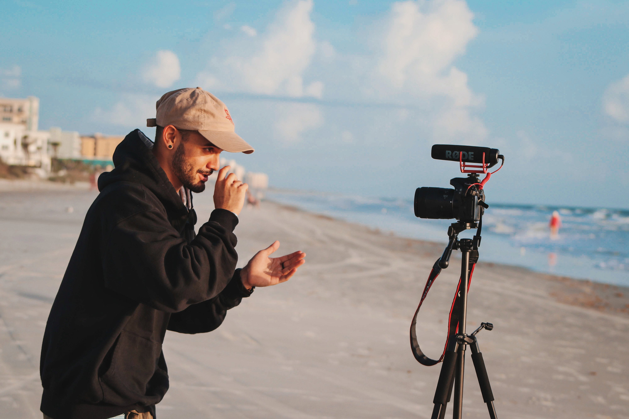 Mann mit Kappe am Strand vor Kamera